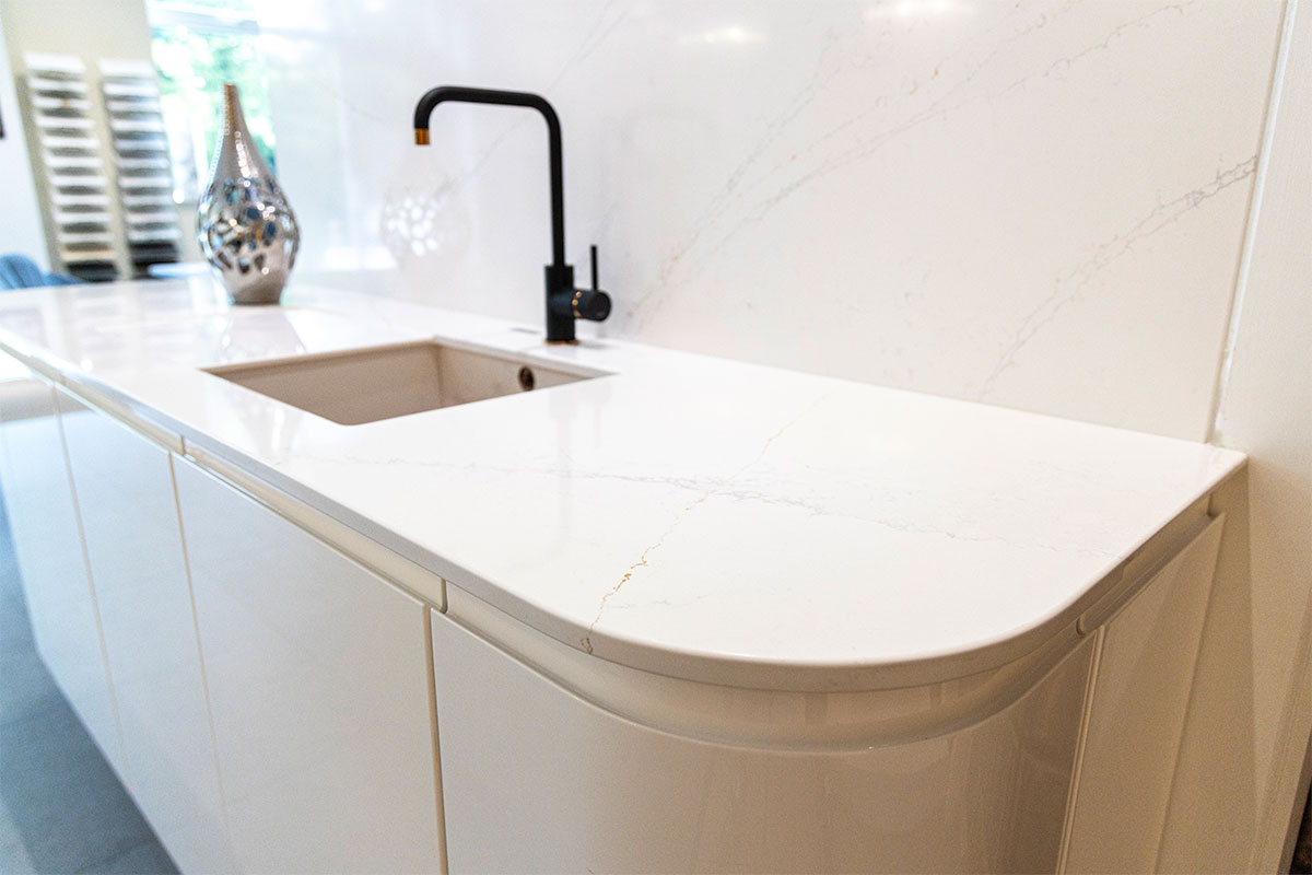 A white Silestone Ethereal Glow marble effect quartz kitchen worktop with matching splashback on display in showroom at LBS Stone in Storrington