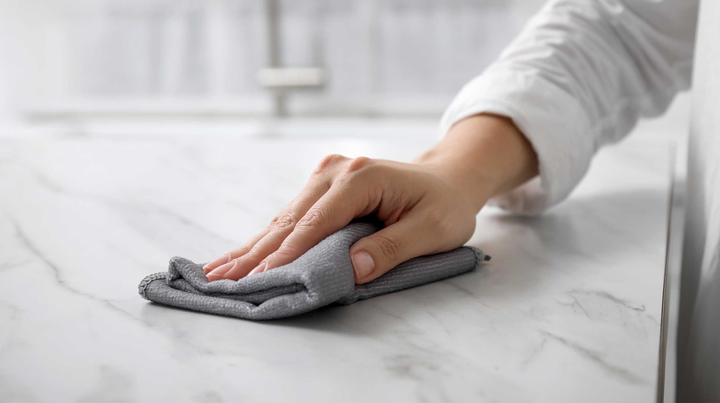 Lady cleaning a quartz or marble stone worktop with a soft microfibre cloth