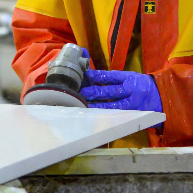 A stone fabrication specialists hand polishing a stone slab in the workshops at LBS Stone in Storrington, West Sussex